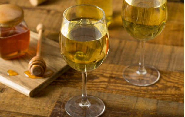 Two glasses of mead beside a honey jar